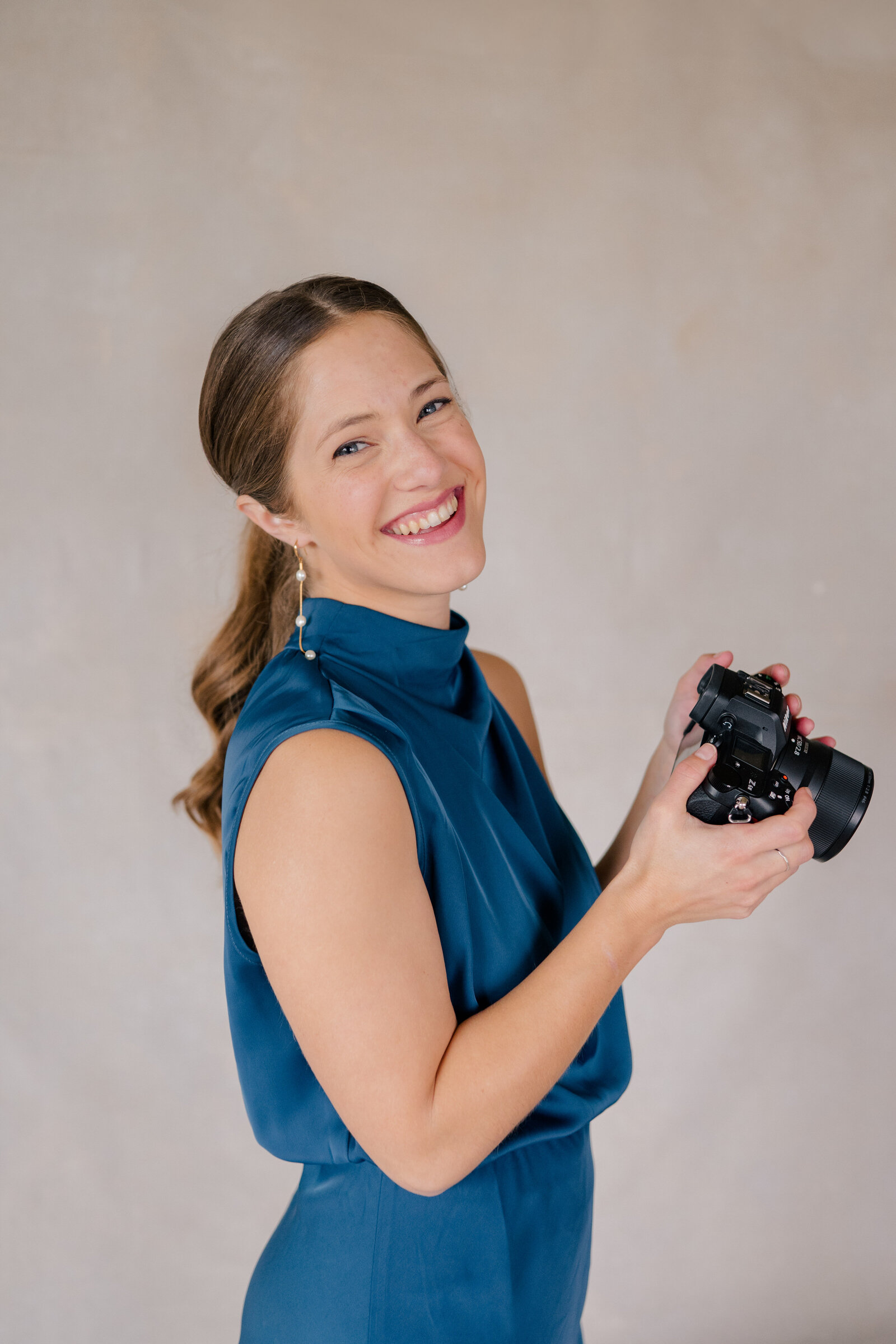 Anna Brace holding her camera and smiling over her shoulder